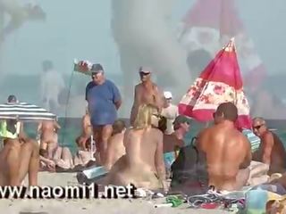 Naomi1 paja un joven tío en un público playa